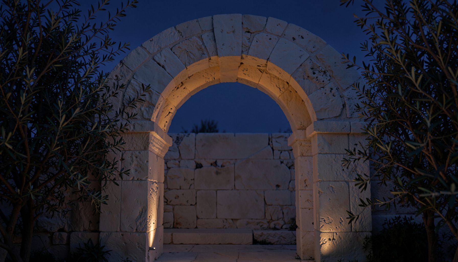 A softly lit stone archway framed by olive branches against a dusky indigo sky, warm ivory stone tones contrasting with deep blue